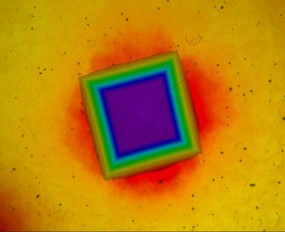 Hot Hardness Indentation at 250°C – Vickers Indent on Metallic Sample Optical microscope view of Vickers hardness indent on metal surface at 250 degrees Celsius with colorful stress field
