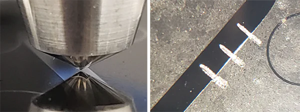 Cross-section-testing-on-the-SMT-5000 Close-up of a diamond indenter tip performing a scratch test next to a coated sample with four scratch tracks and sensor wire